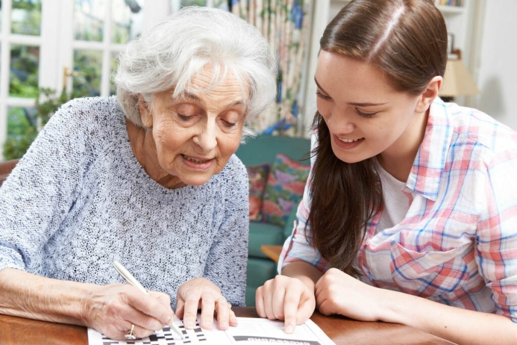 a senior woman and her granddaughter work on a crossword puzzle together