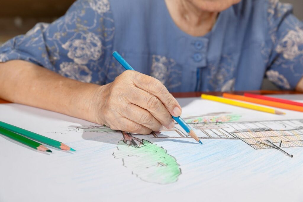 a senior citizen draws and colors in her pad