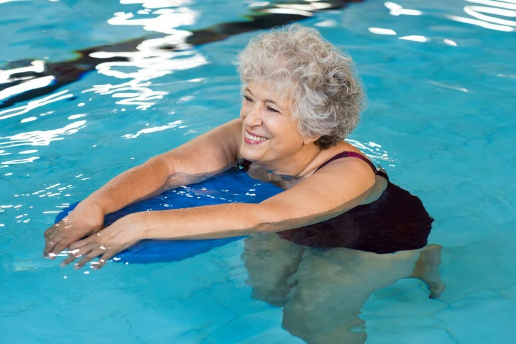 a senior woman enjoys a water class in an indoor pool as one of the best indoor activities for senior citizens