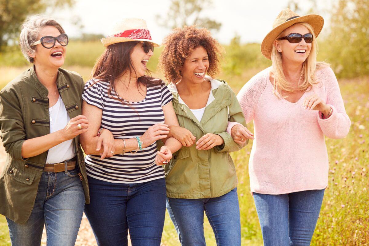 four girlfriends over 50 waking arm in arm and enjoying a sunny afternoon