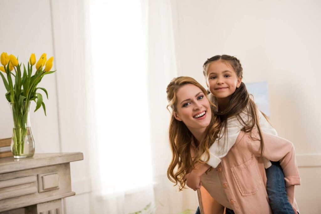 a stay at home mom gives her daughter a piggy back ride