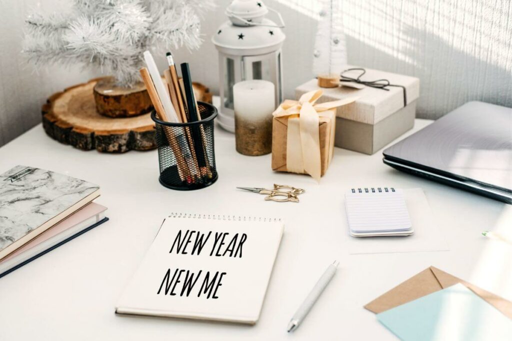 top view of a desk with a pad of paper that says new year new me