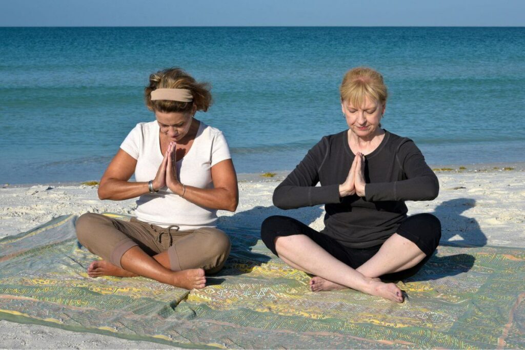 two attractive, confident, and fit middle aged women do yoga on the beach and show they do not care about what not to wear after 50