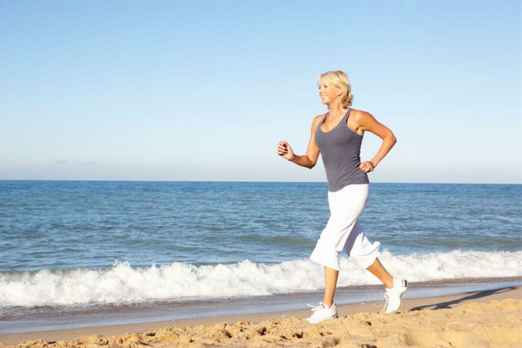 a middle aged woman runs along the beach