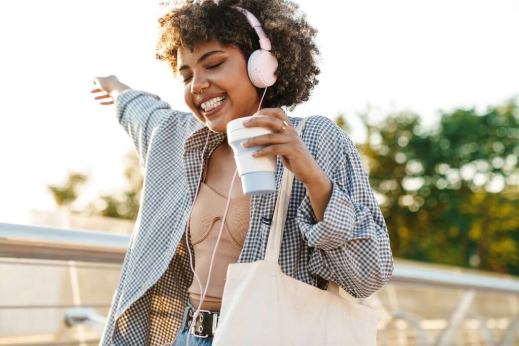 very happy woman listening to her affirmations for letting go on her headset and taking a walk outside