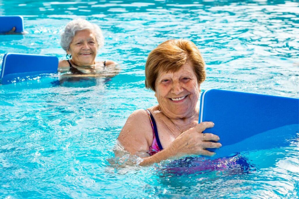 two women using small paddle boards in a pool for exercise