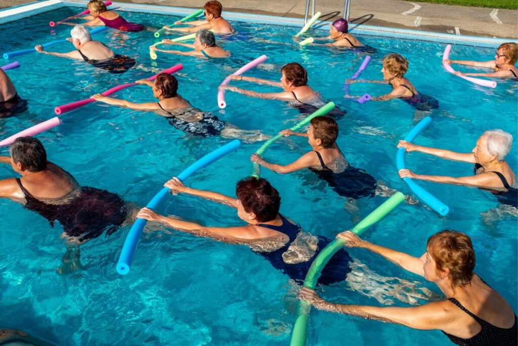 group of adults exercising in an indoor pool because they understand the benefits of swimming for seniors