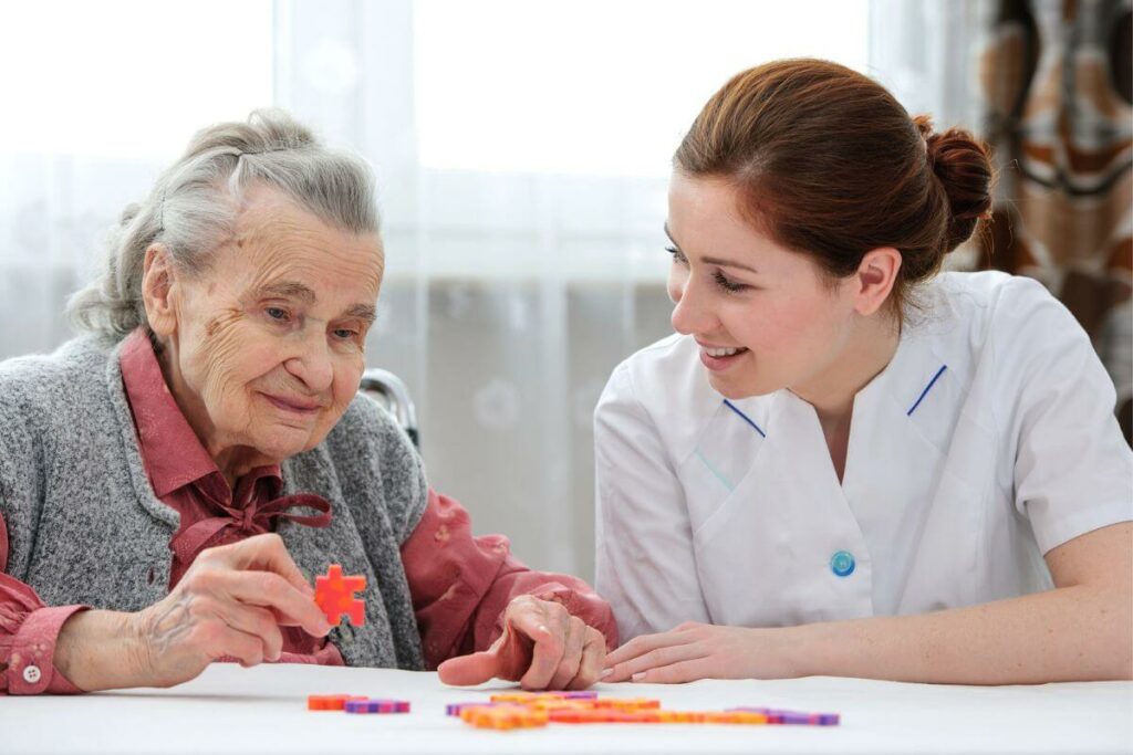 a friendly female caregiver plays a table game with an elderly woman with dementia