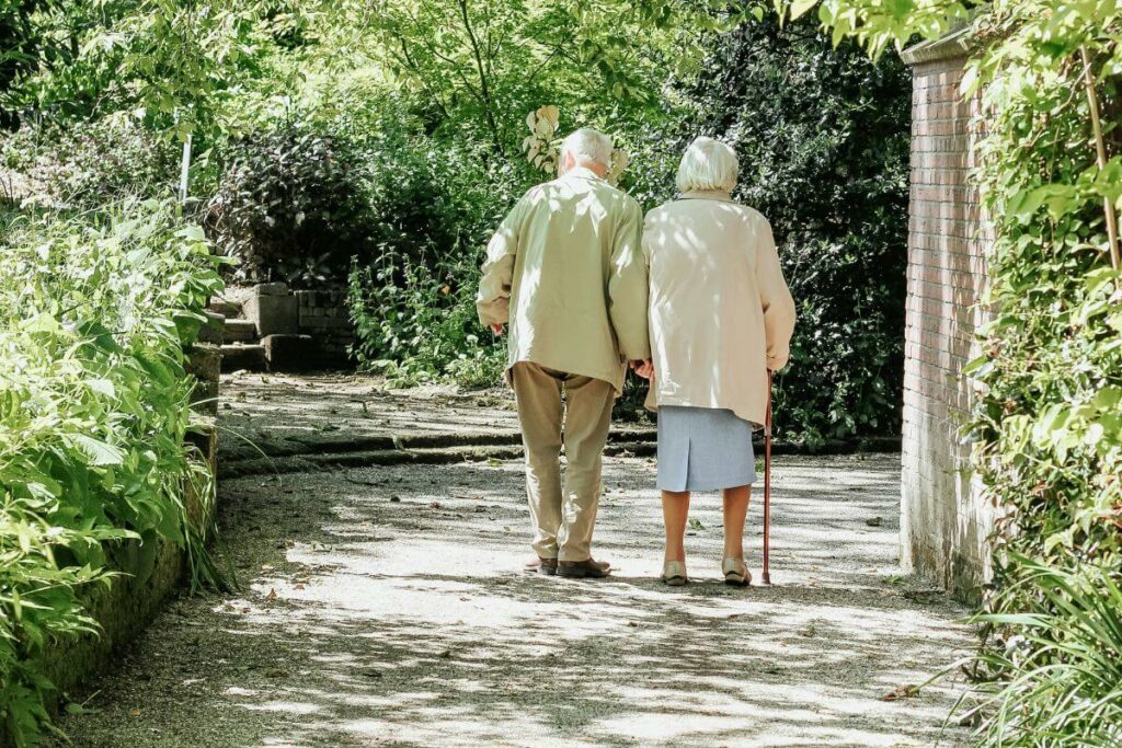 rear view of elderly couple walking along a path in a wooded park