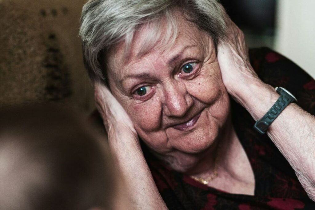 close up of an aging woman covering her ears because she wants to avoid an argument with her daughter