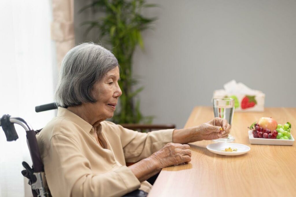 sad elderly Asian woman sitting at a table alone eating a fruit snack