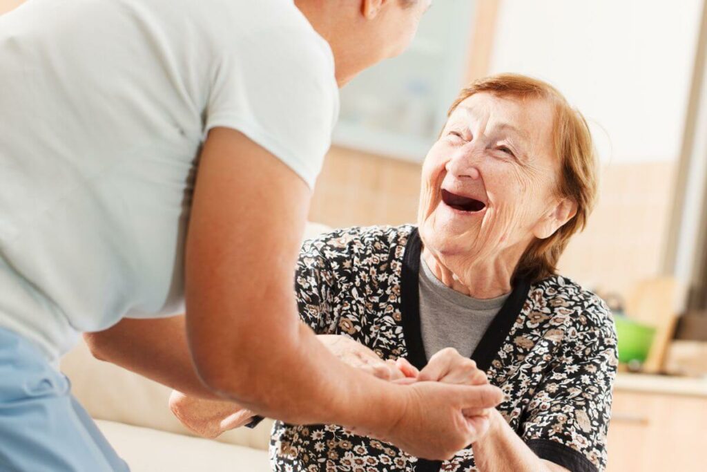 senior woman enthusiastically greets an adult child who warmly holds her hands and uses strategies to avoid arguing with elderly parents