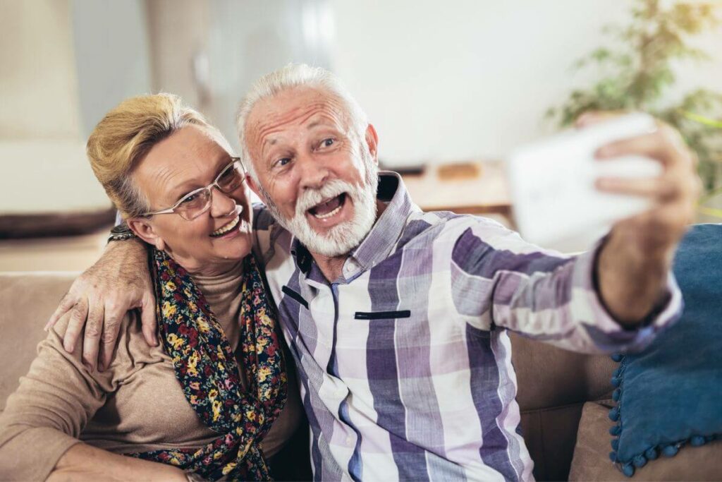 senior husband and wife having fun with list of fun facts for senior citizens as they take a selfie together, showing their advanced technology skills