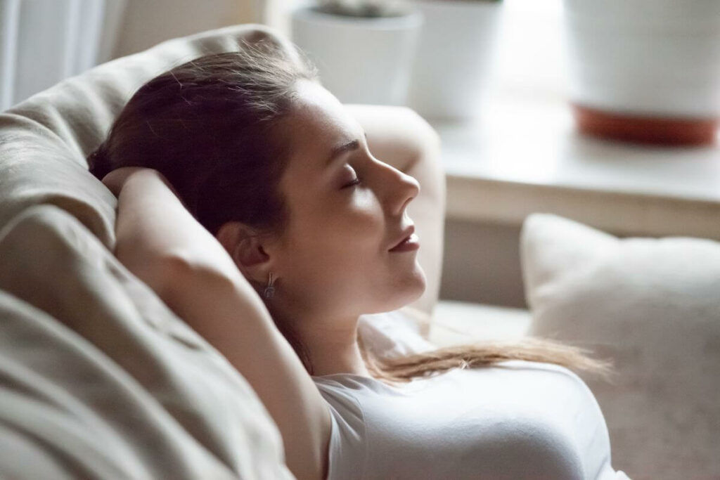 a young woman leaning back in her chair with her eyes shut intentionally relaxing