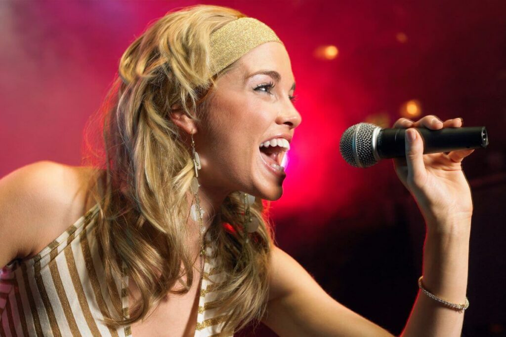 close up of young woman singing songs that empower women into a microphone