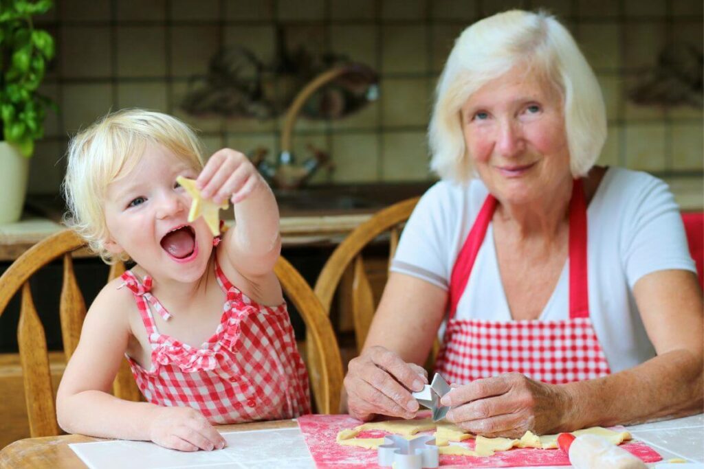 a grandmother and young children bake cookies in their kitchen