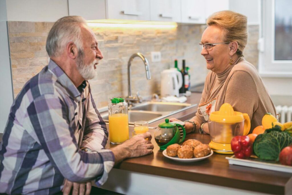 an elderly couple happily enjoy breakfast together after creating an age-inclusive kitchen that is organized and safe