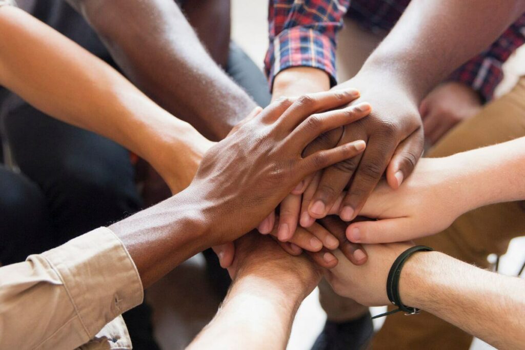 eight hands on top of each other in agreement after a meeting to discuss navigating family dynamics in caregiving.