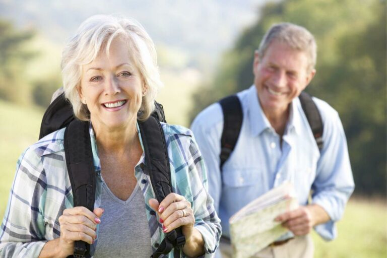 a senior man and woman happily hike through a park together, living and crafting their perfect liefstyle.