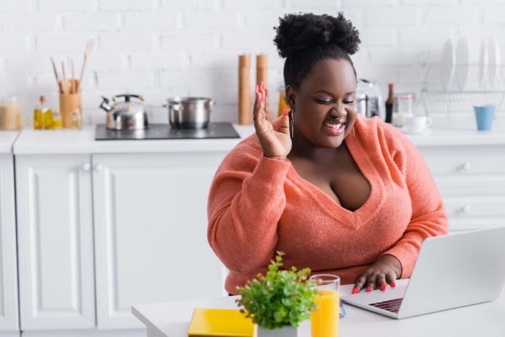 an african american woman sits at a laptop to engage in online advanced education on a journey to create her ideal lifestyle.