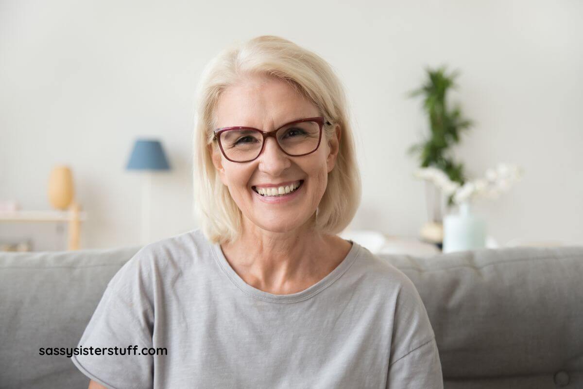 a middle aged woman smiles happily at the camera after making changes and developing good habits for lasting wellness.