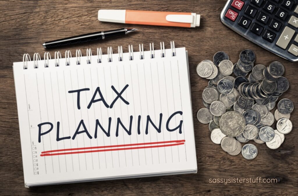 A desk top flat lay with a notebook that say TAX PLANNING next to a pile of coins and a calculator.