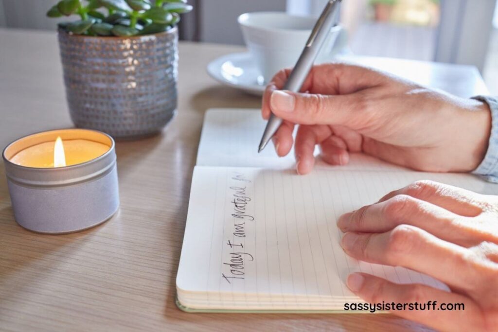 a top view of a woman writing positive affirmations in her journal.