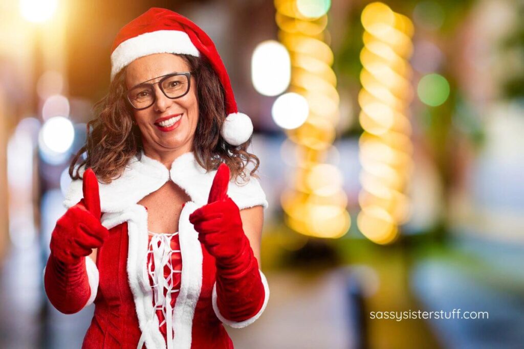 a middle aged woman dressed in a Santa elf oufit gives two thumbs up for an abundance of happiness