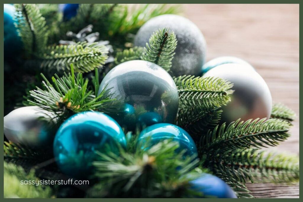 beautiful Christmas tree ornaments in turquoise and silver laying in greenery