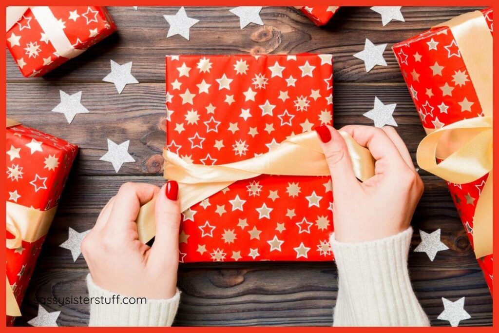 top view of a woman wrapping Christmas gifts, creating a big bow on a package