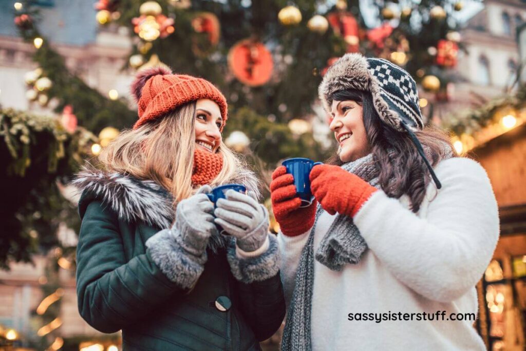 two smiling women on a cold winter day drink hot chocolate together for the featured image for Inspirational December Quotes