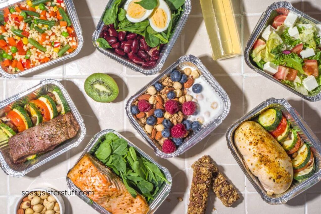 top view of healthy foods that include trays of vegetables, proteins, fruits, and grains