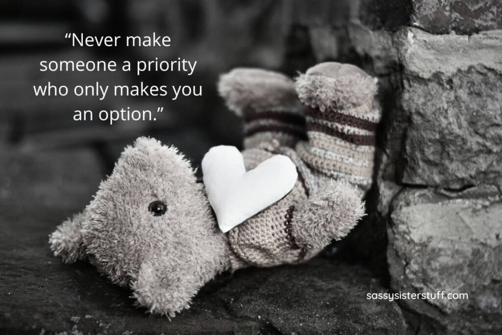 Quote: Never make someone a priority who only makes you an option. Black and white photo of a teddy bear laying on the ground.