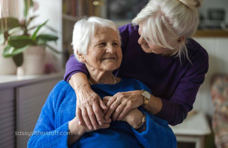 middle aged woman hugs her elderly mom and talks quietly with her.