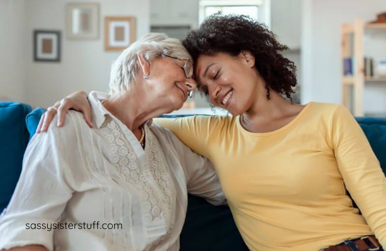 an adult female sits head to hear with her aging mother as they have a pleasant conversation.