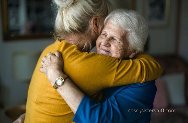 an adult woman and her aging mother hug each other after a sweet discussion.