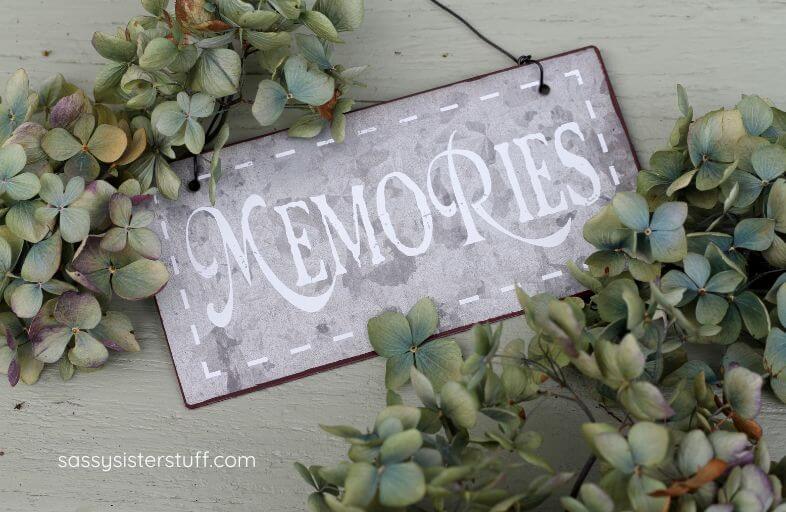 a sign that says MEMORIES with greenery around it.