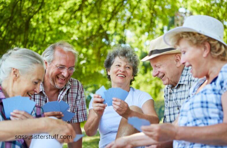 a group of senior citizens play a game and chat outside on a sunny day