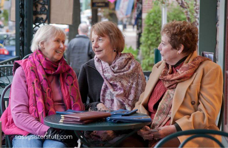 three senior citizens enjoy a chat at a sidewalk cafe