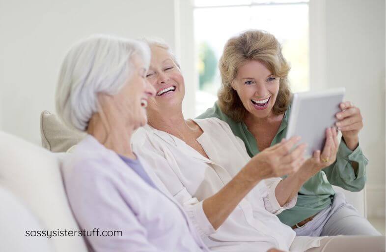 there older women laugh together as they chat and look at a photo