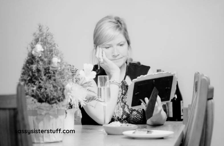 a black and white image of a sad mom looking at a photo feeling empty nest syndrome.