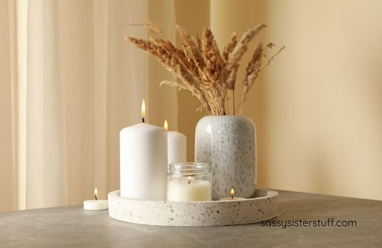 close-up of a tray with five candles and a vase of dried fountain grass.