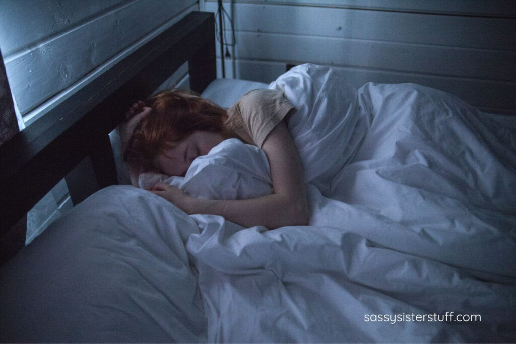 woman sleeping in a dark cozy bedroom.