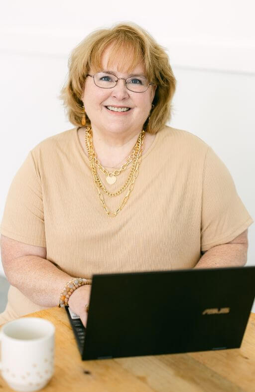 female writer typing on her laptop and smiling at the camera