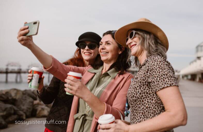 three happy middle aged female friends take a self on the boardwalk