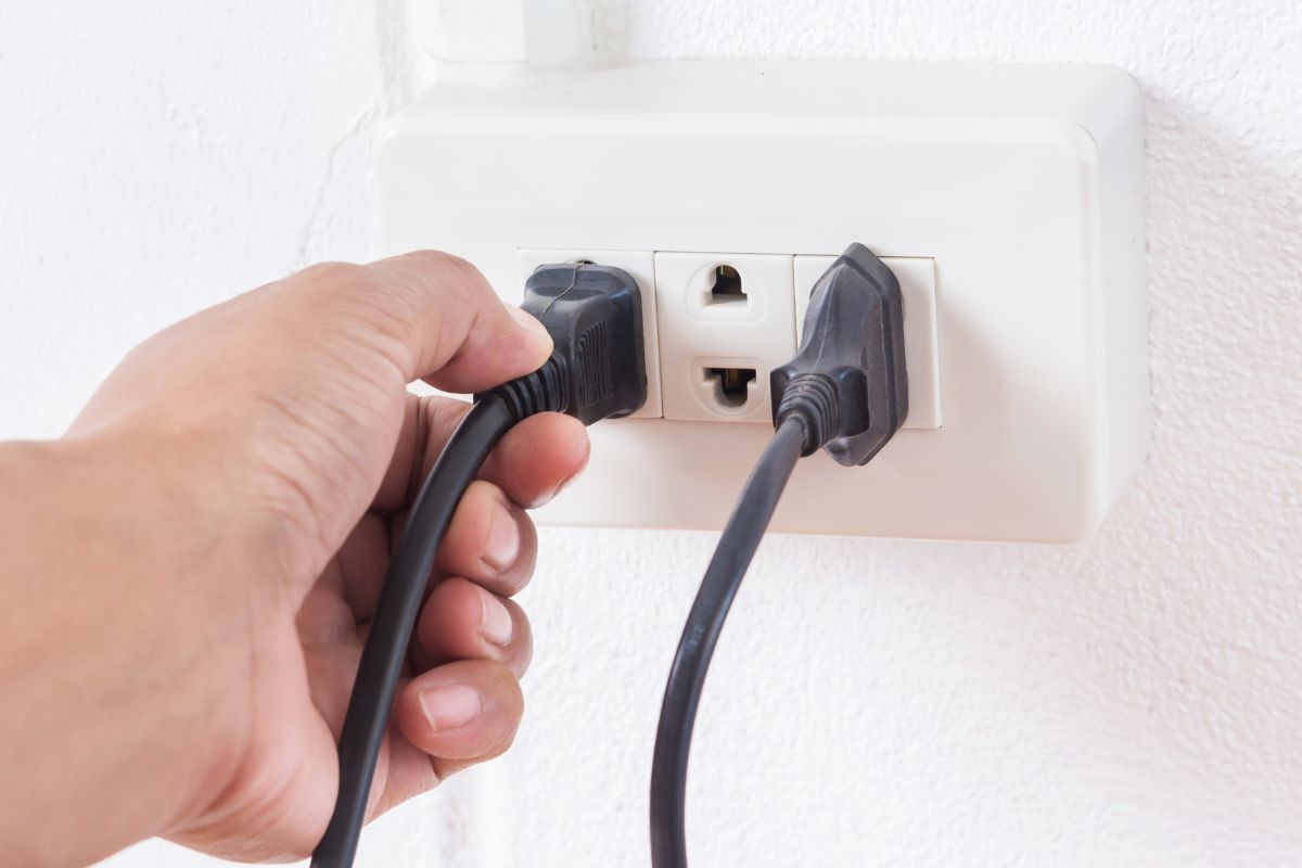 a hand unplugging from an outlet