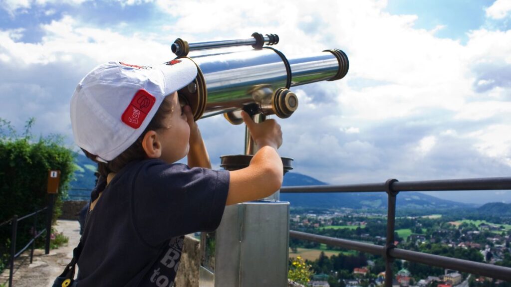 boy looking through telescope at clouds