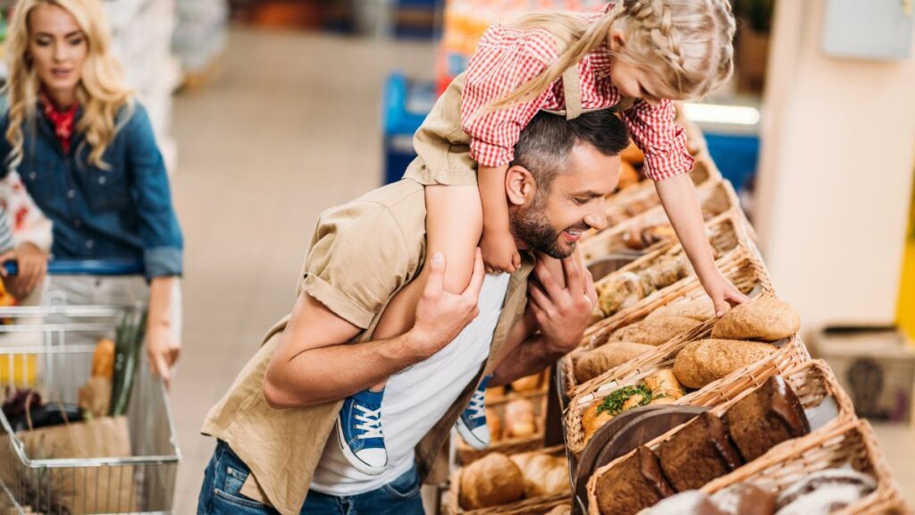 father and daughter picking bread at grocery store