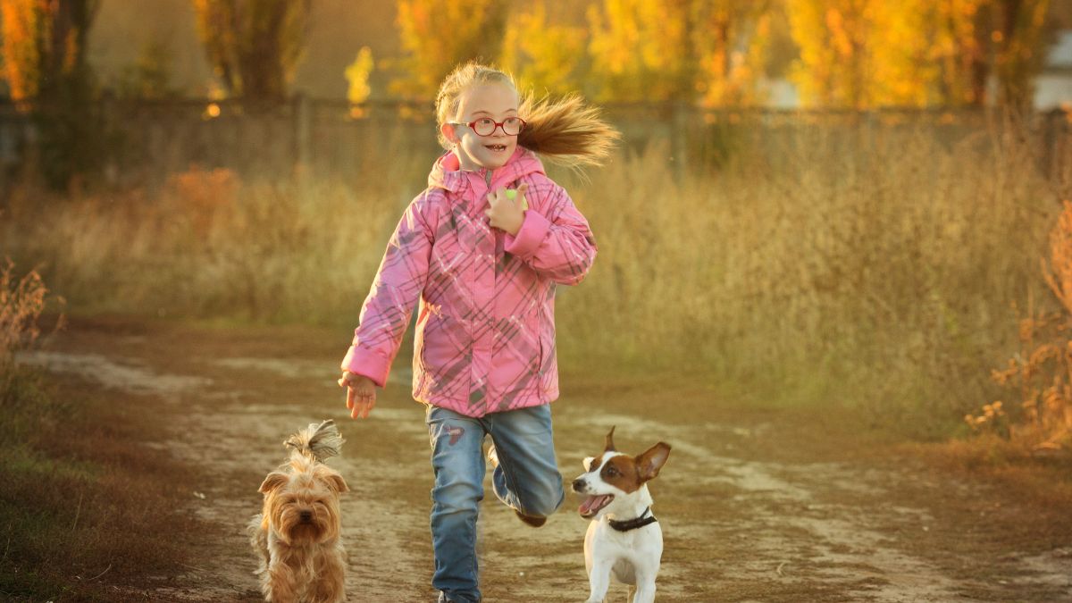 girl with special needs running with dogs outside