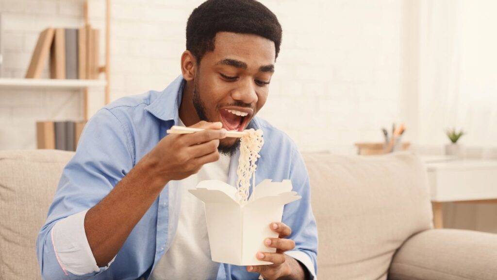 man eating takeout noodles